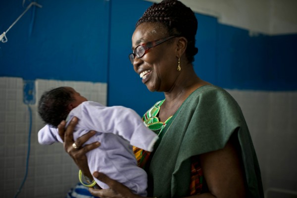 Marion Subah, Jhpiego’s Medical Education and Training Advisor in Liberia, holds a newborn baby in the newly built maternity wing of the public hospital in Buchanan, Liberia. (Photo credit: Jhpiego/Kate Holt)