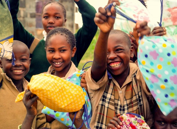 Girls in Kenya hold up their Days for Girls Kits. (Photo credit: Days for Girls)